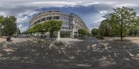 a fish - eye lens view of a building next to a park with lots of trees