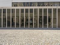 the facade of a modern building with big windows on one side and multiple small rectangular tiles on the other