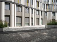 a man riding a bicycle past an office building with an outside courtyard on a sunny day