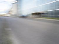 blurred, long - exposure view of an empty road with building in the background from behind a parked motorcycle