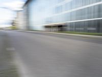 blurred, long - exposure view of an empty road with building in the background from behind a parked motorcycle