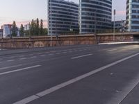 empty street by an overpass with buildings in the background and people on the sidewalk waiting for the traffic