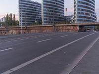 empty street by an overpass with buildings in the background and people on the sidewalk waiting for the traffic