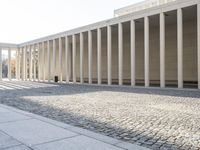 a building with columns that have been built over the floor to make a walkway across it