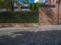 a long empty brick street with tall buildings in the background on a sunny day with some people walking around