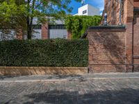 a long empty brick street with tall buildings in the background on a sunny day with some people walking around