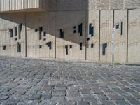 cobblestone driveway surrounded by modern buildings on sunny day with sun reflecting onto the windows