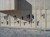 cobblestone driveway surrounded by modern buildings on sunny day with sun reflecting onto the windows