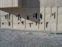 cobblestone driveway surrounded by modern buildings on sunny day with sun reflecting onto the windows