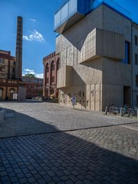 cobblestone driveway surrounded by modern buildings on sunny day with sun reflecting onto the windows