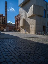 cobblestone driveway surrounded by modern buildings on sunny day with sun reflecting onto the windows