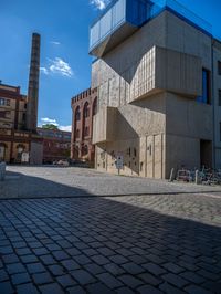 cobblestone driveway surrounded by modern buildings on sunny day with sun reflecting onto the windows