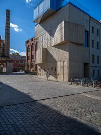 cobblestone driveway surrounded by modern buildings on sunny day with sun reflecting onto the windows