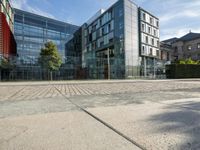 a modern office building with two glass windows near brick walk and fenced in front