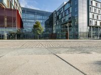 a modern office building with two glass windows near brick walk and fenced in front