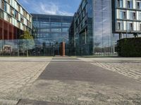 a modern office building with two glass windows near brick walk and fenced in front