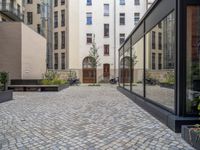 an empty parking lot with plants in the ground and on the side of the building, there is an enclosed area and windows