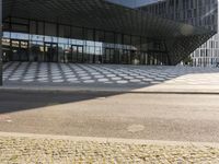 two people riding on a red bicycle on a city street in the sunlight at the entrance of a building