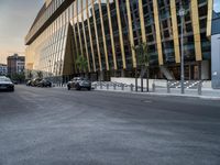 a car traveling down the middle of a street next to tall buildings with lots of windows