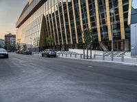 a car traveling down the middle of a street next to tall buildings with lots of windows