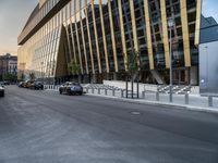 a car traveling down the middle of a street next to tall buildings with lots of windows