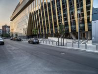 a car traveling down the middle of a street next to tall buildings with lots of windows