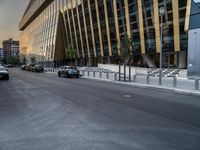 a car traveling down the middle of a street next to tall buildings with lots of windows