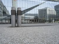 the building has three large posts in front of it on a cobble stone sidewalk