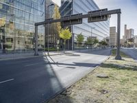 a road leading to buildings that have glass walls on them and a light pole with no people standing at the bottom