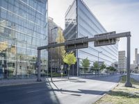 a road leading to buildings that have glass walls on them and a light pole with no people standing at the bottom