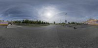 the picture is fish eye view of a skateboarder riding his board on an empty parking lot