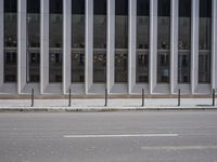 an empty street is lined with long vertical poles that have been placed on the wall