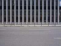 an empty street is lined with long vertical poles that have been placed on the wall
