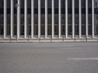 an empty street is lined with long vertical poles that have been placed on the wall