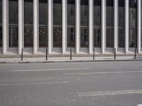 an empty street is lined with long vertical poles that have been placed on the wall