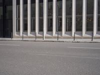 an empty street is lined with long vertical poles that have been placed on the wall