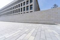 a brick path that is in front of an office building and a wall on the side of it