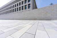 a brick path that is in front of an office building and a wall on the side of it