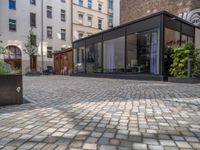 an empty parking lot with plants in the ground and on the side of the building, there is an enclosed area and windows