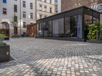 an empty parking lot with plants in the ground and on the side of the building, there is an enclosed area and windows