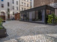 an empty parking lot with plants in the ground and on the side of the building, there is an enclosed area and windows