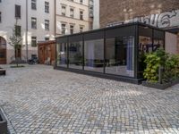 an empty parking lot with plants in the ground and on the side of the building, there is an enclosed area and windows