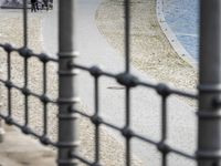 a woman walking next to the water near a bench and fence with a bird in it