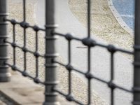 a woman walking next to the water near a bench and fence with a bird in it