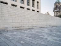 this image has an empty wall and buildings in the background and a man skateboarding