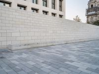 this image has an empty wall and buildings in the background and a man skateboarding