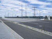 the highway is empty for traffic and has street lamps and tall poles on it and some blue sky