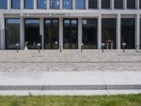 a brick building with glass windows and sidewalk leading to it and a black fire hydrant