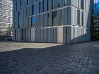 cobblestone driveway surrounded by modern buildings on sunny day with sun reflecting onto the windows