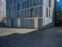 cobblestone driveway surrounded by modern buildings on sunny day with sun reflecting onto the windows